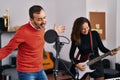 Middle age man and woman musicians playing electric guitar singing song at music studio Royalty Free Stock Photo