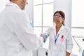 Middle age man and woman partners wearing scientist uniform shake hands at laboratory