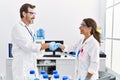 Middle age man and woman partners wearing scientist uniform shake hands at laboratory