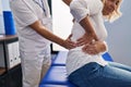 Middle age man and woman physiotherapist and patient massaging back having rehab session at physiotherapy clinic