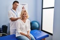 Middle age man and woman physiotherapist and patient massaging neck having rehab session at physiotherapy clinic Royalty Free Stock Photo