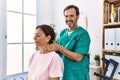 Middle age man and woman smiling confident massaging neck having rehab session at physiotherapy clinic Royalty Free Stock Photo