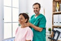 Middle age man and woman smiling confident massaging neck having rehab session at physiotherapy clinic Royalty Free Stock Photo