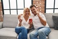 Middle age man and woman using smartphone sitting on the sofa surprised with an idea or question pointing finger with happy face, Royalty Free Stock Photo