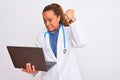Middle age mature doctor woman holding computer laptop over isolated background annoyed and frustrated shouting with anger, crazy Royalty Free Stock Photo
