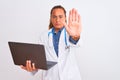 Middle age mature doctor woman holding computer laptop over isolated background with open hand doing stop sign with serious and Royalty Free Stock Photo