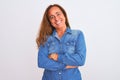 Middle age mature woman wearing denim jacket standing over white isolated background happy face smiling with crossed arms looking Royalty Free Stock Photo