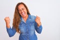 Middle age mature woman wearing denim jacket standing over white isolated background very happy and excited doing winner gesture Royalty Free Stock Photo