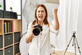 Middle age photography woman using camera at photo studio annoyed and frustrated shouting with anger, yelling crazy with anger and