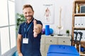 Middle age physiotherapist man working at pain recovery clinic smiling friendly offering handshake as greeting and welcoming Royalty Free Stock Photo