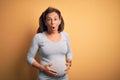 Middle age pregnant woman expecting baby at aged pregnancy afraid and shocked with surprise expression, fear and excited face Royalty Free Stock Photo