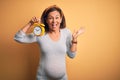 Middle age pregnant woman expecting baby at aged pregnancy holding alarm clock very happy and excited, winner expression Royalty Free Stock Photo