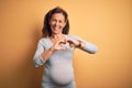 Middle age pregnant woman expecting baby at aged pregnancy smiling in love showing heart symbol and shape with hands Royalty Free Stock Photo