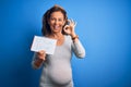 Middle Age Pregnant Woman Expecting Baby Boy Over Blue Background Doing Ok Sign With Fingers, Excellent Symbol