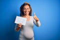 Middle age pregnant woman expecting baby boy over blue background happy with big smile doing ok sign, thumb up with fingers, Royalty Free Stock Photo