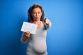 Middle age pregnant woman expecting baby boy over blue background pointing with finger to the camera and to you, hand sign, Royalty Free Stock Photo