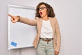 Middle age senior business woman standing on seminar presentation by magnectic blackboard Pointing with finger surprised ahead, Royalty Free Stock Photo