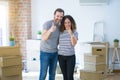 Middle age senior couple moving to a new home with boxes around doing happy thumbs up gesture with hand Royalty Free Stock Photo