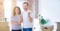 Middle age senior couple moving to a new home with boxes around smiling with happy face looking and pointing to the side with Royalty Free Stock Photo