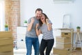 Middle age senior couple moving to a new home with boxes around very happy and excited doing winner gesture with arms raised, Royalty Free Stock Photo