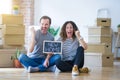 Middle age senior couple sitting on the floor holding blackboard moving to a new home screaming proud and celebrating victory and Royalty Free Stock Photo