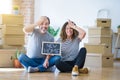 Middle age senior couple sitting on the floor holding blackboard moving to a new home stressed with hand on head, shocked with Royalty Free Stock Photo