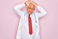 Middle age senior grey-haired doctor man wearing stethoscope and professional medical coat Doing bunny ears gesture with hands Royalty Free Stock Photo