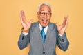 Middle age senior grey-haired handsome business man wearing glasses over yellow background celebrating crazy and amazed for Royalty Free Stock Photo