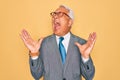 Middle age senior grey-haired handsome business man wearing glasses over yellow background celebrating mad and crazy for success Royalty Free Stock Photo