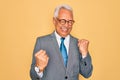 Middle age senior grey-haired handsome business man wearing glasses over yellow background celebrating surprised and amazed for Royalty Free Stock Photo