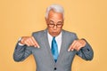 Middle age senior grey-haired handsome business man wearing glasses over yellow background Pointing down with fingers showing Royalty Free Stock Photo