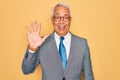 Middle age senior grey-haired handsome business man wearing glasses over yellow background showing and pointing up with fingers Royalty Free Stock Photo