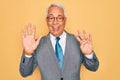 Middle age senior grey-haired handsome business man wearing glasses over yellow background showing and pointing up with fingers Royalty Free Stock Photo