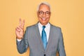 Middle age senior grey-haired handsome business man wearing glasses over yellow background showing and pointing up with fingers Royalty Free Stock Photo