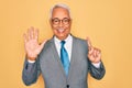 Middle age senior grey-haired handsome business man wearing glasses over yellow background showing and pointing up with fingers Royalty Free Stock Photo