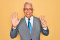 Middle age senior grey-haired handsome business man wearing glasses over yellow background showing and pointing up with fingers Royalty Free Stock Photo