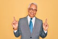 Middle age senior grey-haired handsome business man wearing glasses over yellow background smiling confident pointing with fingers Royalty Free Stock Photo