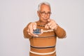 Middle age senior grey-haired man using tv remote control watching television pointing with finger to the camera and to you, hand Royalty Free Stock Photo