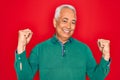 Middle age senior grey-haired man wearing casual sweater over red isoalted background celebrating surprised and amazed for success Royalty Free Stock Photo