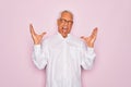 Middle age senior grey-haired man wearing glasses and business shirt over pink background celebrating mad and crazy for success Royalty Free Stock Photo