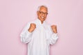 Middle age senior grey-haired man wearing glasses and business shirt over pink background excited for success with arms raised and Royalty Free Stock Photo