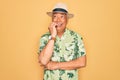 Middle age senior grey-haired man wearing summer hat and floral shirt on beach vacation looking stressed and nervous with hands on Royalty Free Stock Photo