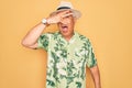 Middle age senior grey-haired man wearing summer hat and floral shirt on beach vacation peeking in shock covering face and eyes Royalty Free Stock Photo