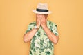 Middle age senior grey-haired man wearing summer hat and floral shirt on beach vacation with sad expression covering face with Royalty Free Stock Photo