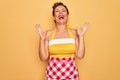 Middle age senior pin up housewife woman wearing 50s style retro dress and apron celebrating mad and crazy for success with arms Royalty Free Stock Photo