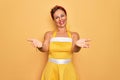 Middle age senior pin up woman wearing 50s style retro dress over yellow background smiling cheerful offering hands giving Royalty Free Stock Photo