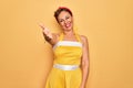 Middle age senior pin up woman wearing 50s style retro dress over yellow background smiling cheerful offering palm hand giving Royalty Free Stock Photo