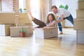 Middle age senior romantic couple having fun riding inside of cardboard, excited and smiling happy for moving to a new home