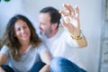 Middle age senior romantic couple in love sitting on the apartment floor with cardboard boxes around and showing house keys Royalty Free Stock Photo