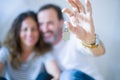 Middle age senior romantic couple in love sitting on the apartment floor with cardboard boxes around and showing house keys Royalty Free Stock Photo